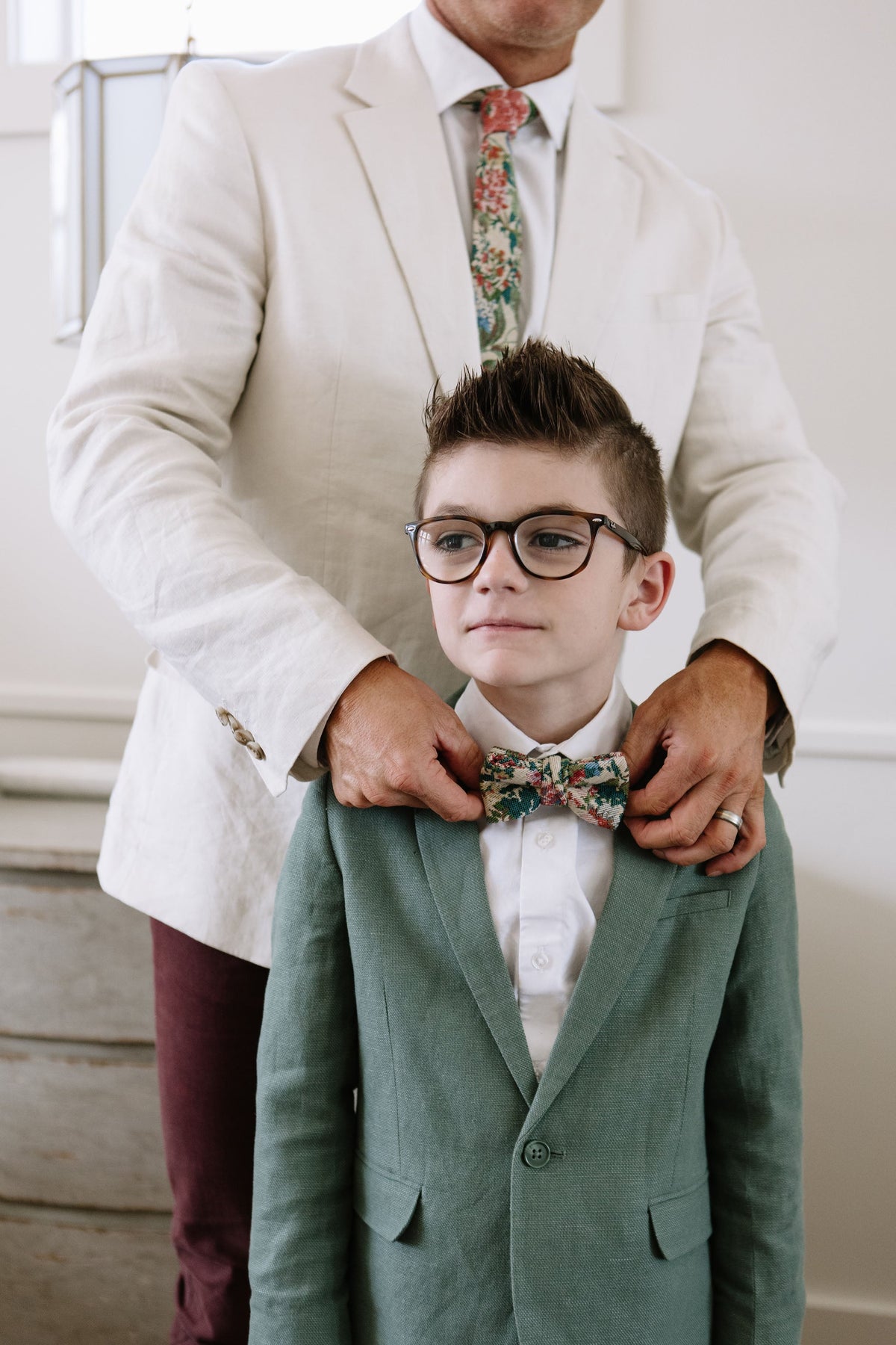 Boys multicolor plaid bow tie on a white shirt with a green vest.