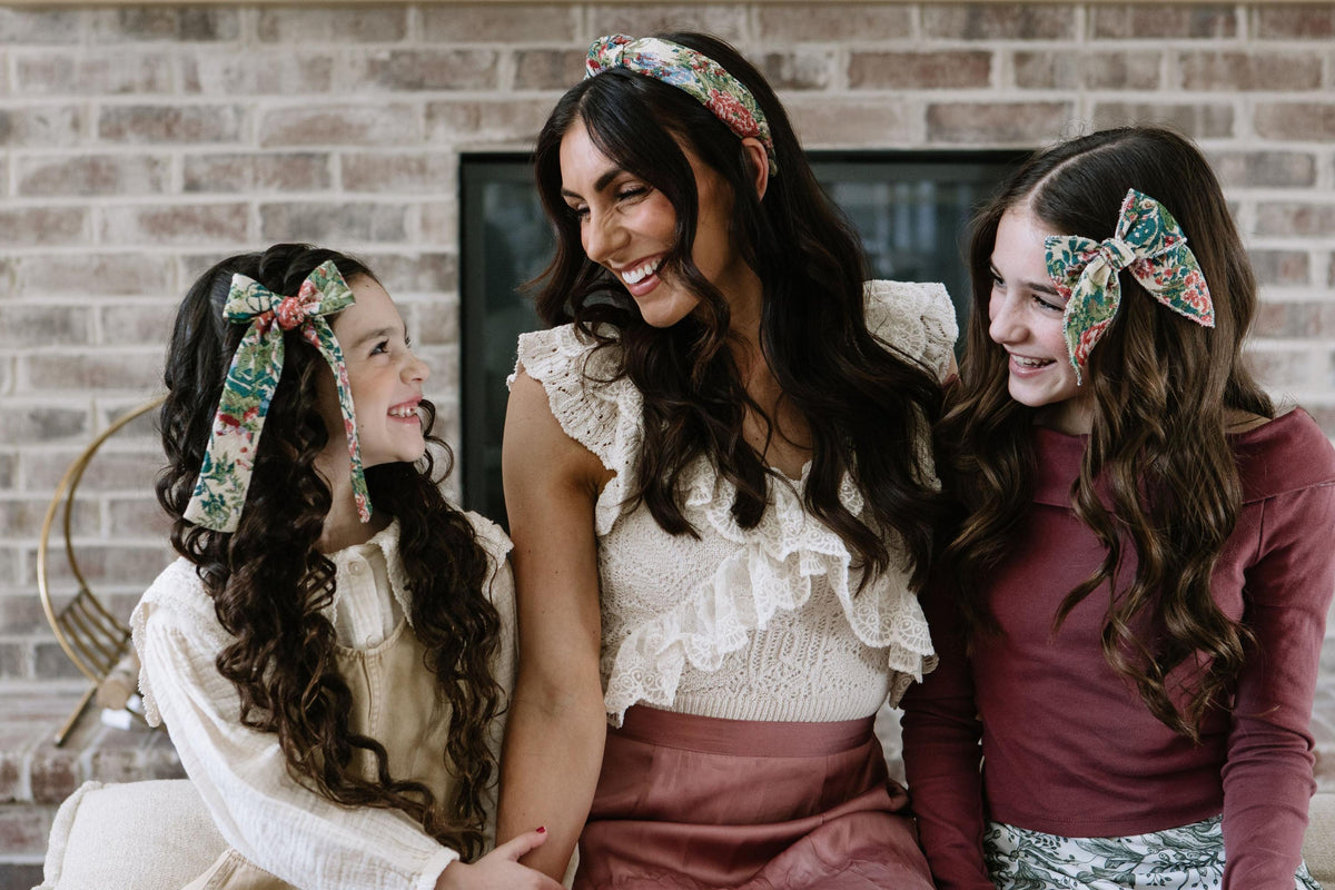 Two children wearing multicolor floral plaid hair bows with long ribbon tails