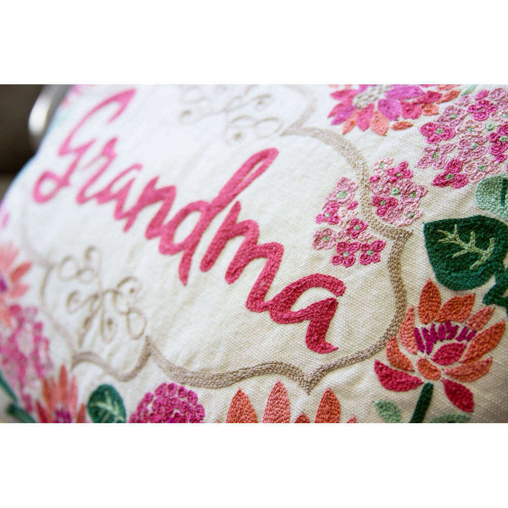 Close-up embroidered 'Grandma' lettering with pink and green floral stitches on white