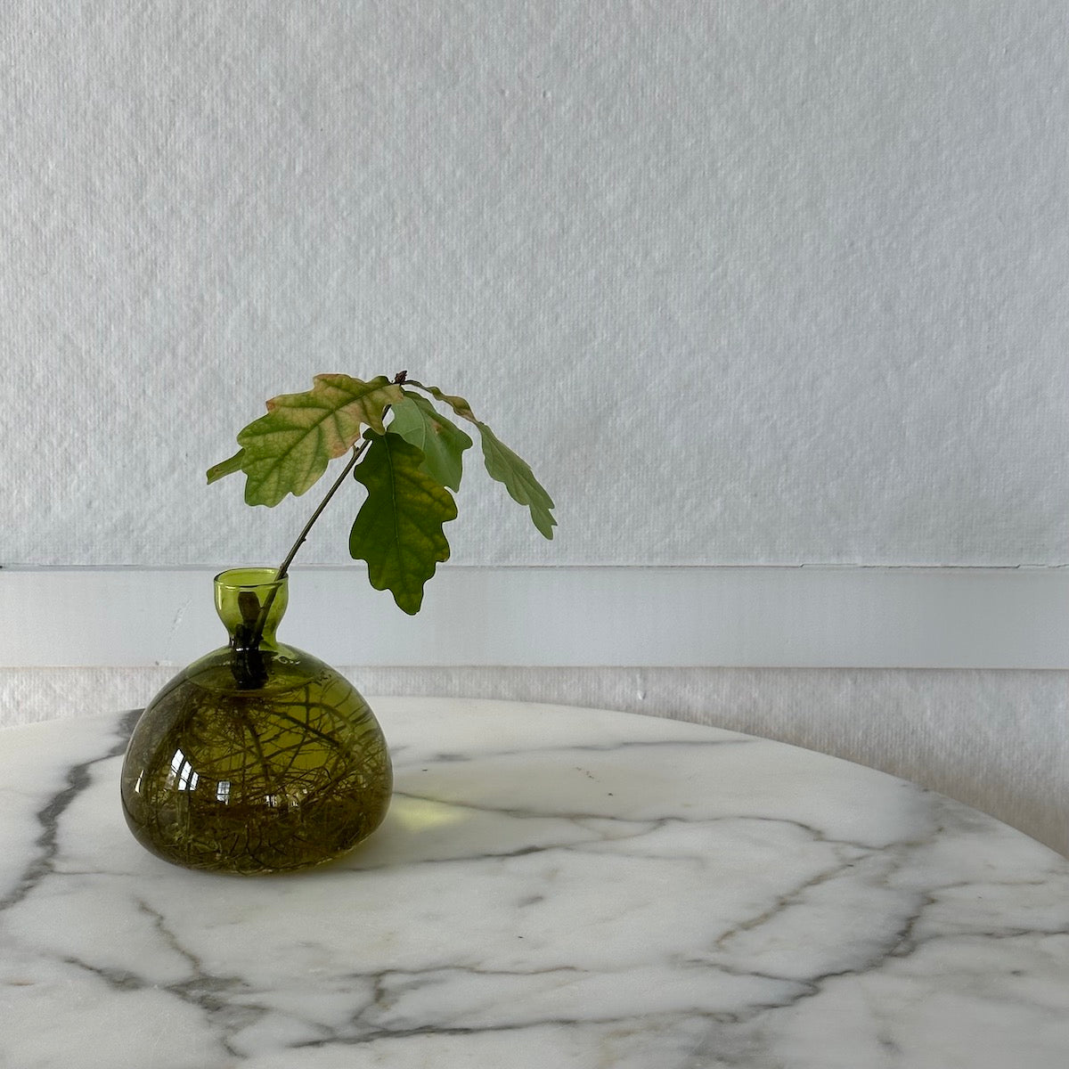 Grass green acorn-shaped glass vase with leafy stem, rounded bulb body