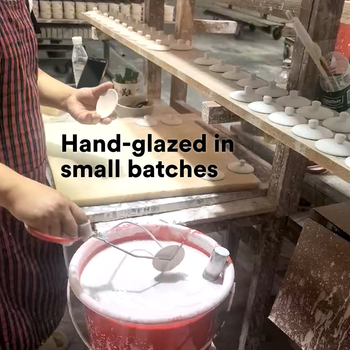 Glazing station view: hand holding beige ceramic box with forest motif and white lid