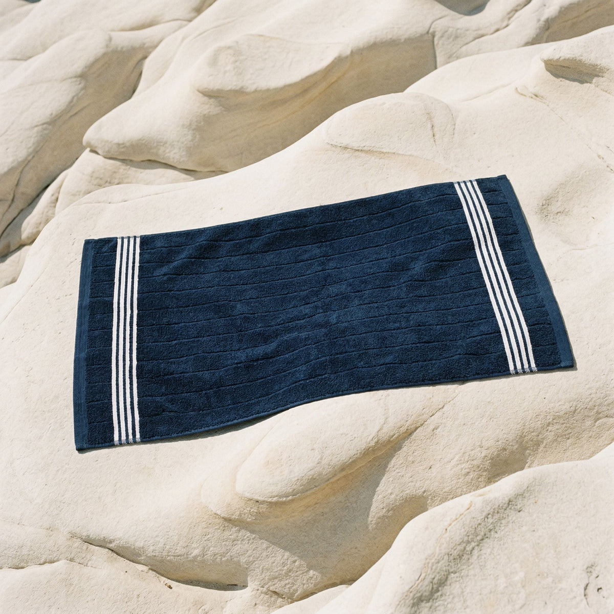 Rectangular navy cotton towel with white stripe bands