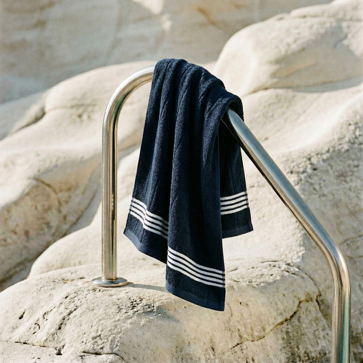 Navy cotton hand towel with white stripe bands hanging on a metal stand