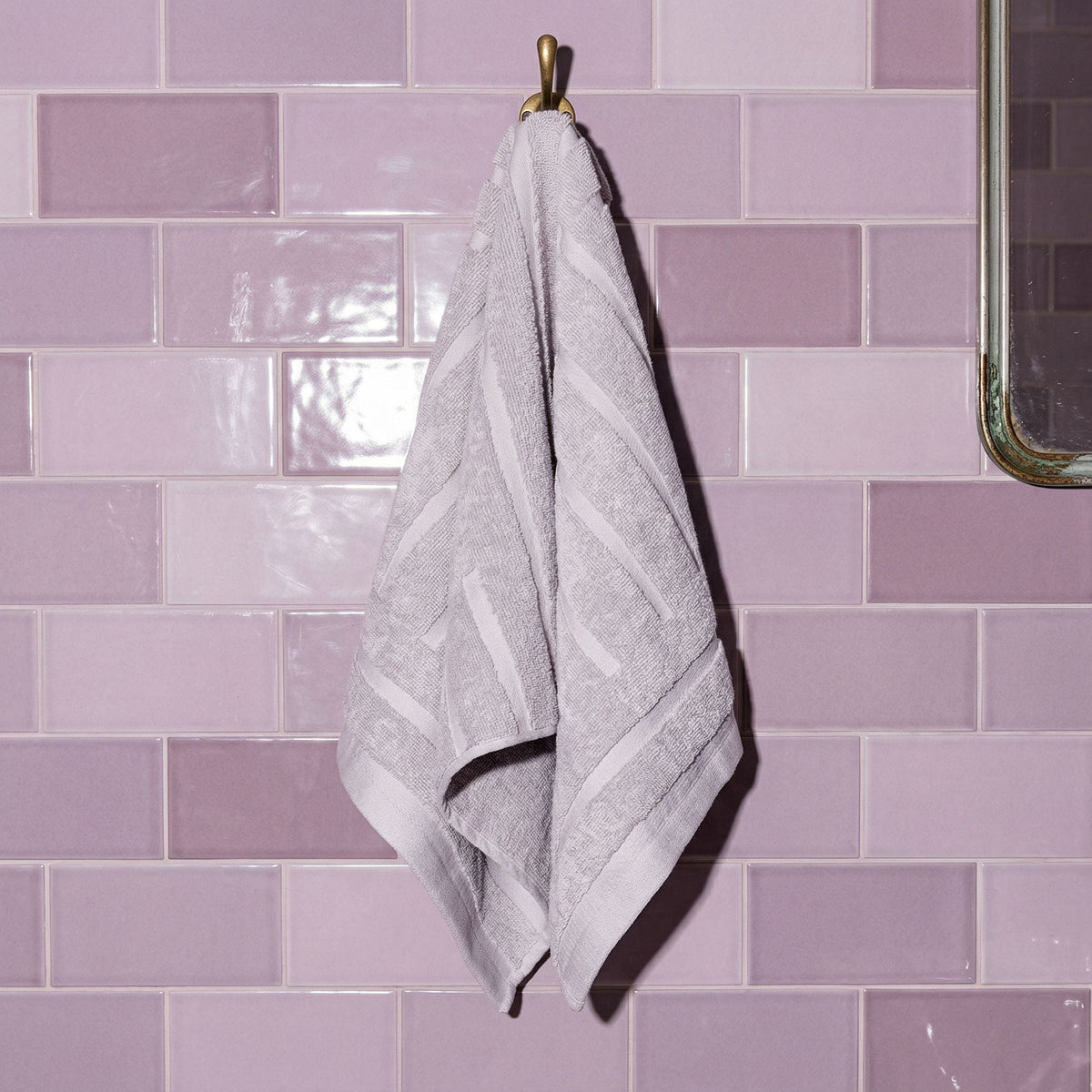 Light gray cotton hand towel hanging, terry texture with stitched border trim