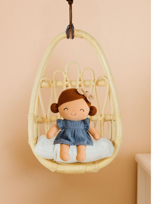 Handwoven natural rattan doll chair with a white cushion, shown holding a seated doll