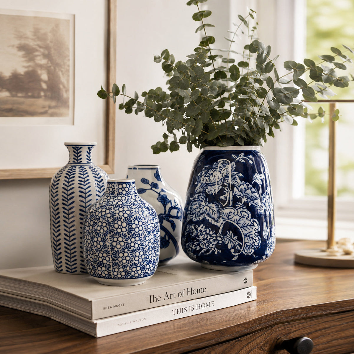 Blue-and-white ceramic vases on a wooden shelf with leafy decor