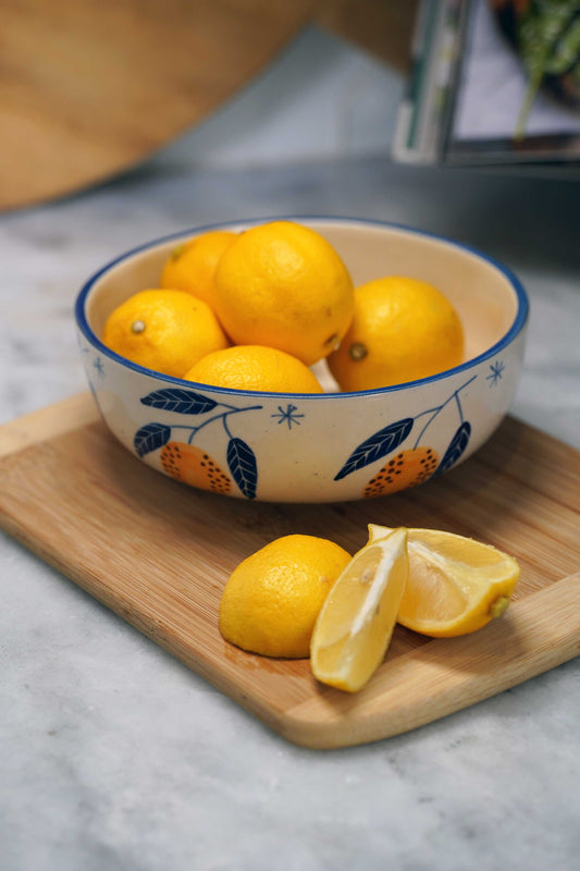 Lemon serving bowl with blue leaf pattern, filled with yellow lemons and sliced lemon