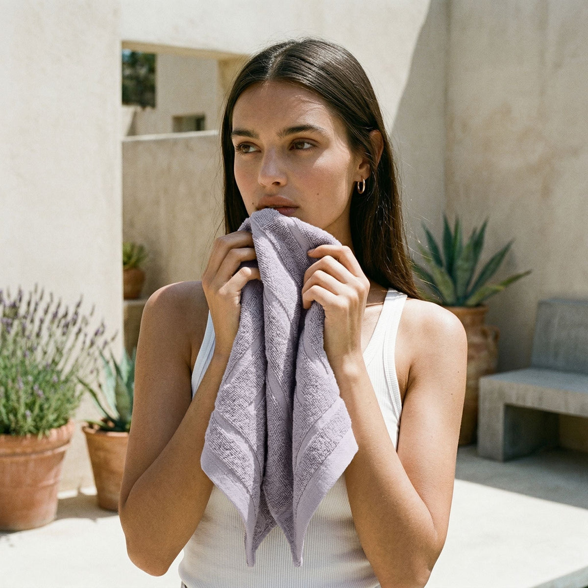 Lavender washcloth with vertical stripe texture, held folded at chest level.
