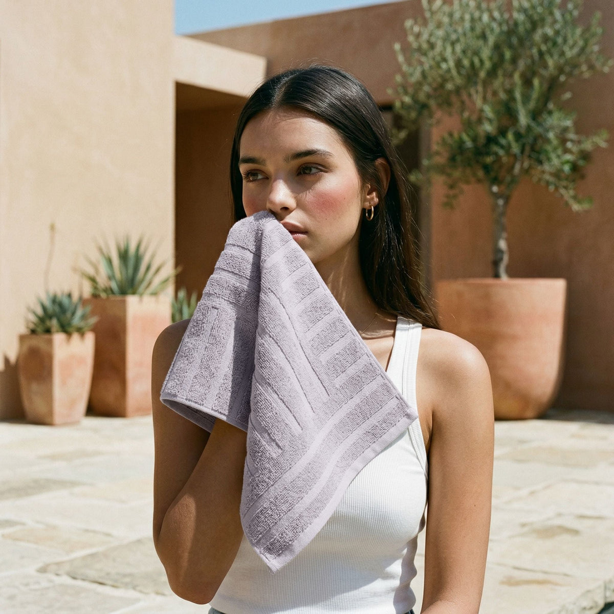 Lavender towel with vertical stripe texture, folded and held beside the body.