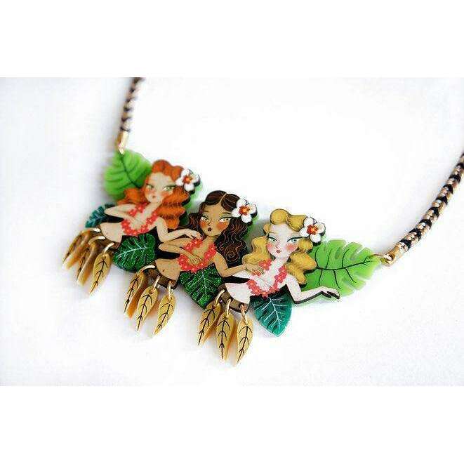 Hula girls necklace close-up: three girl charms with green leaves and dangling gold tails