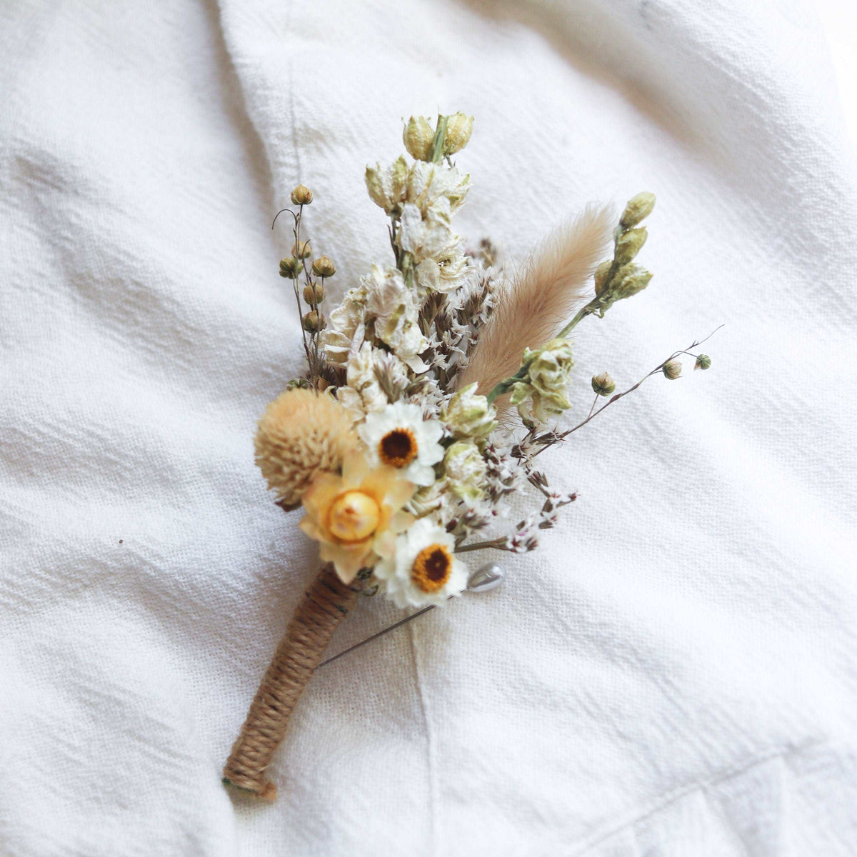 Small dried flower bouquet with cream strawflowers and tiny buds on twine-wrapped handle