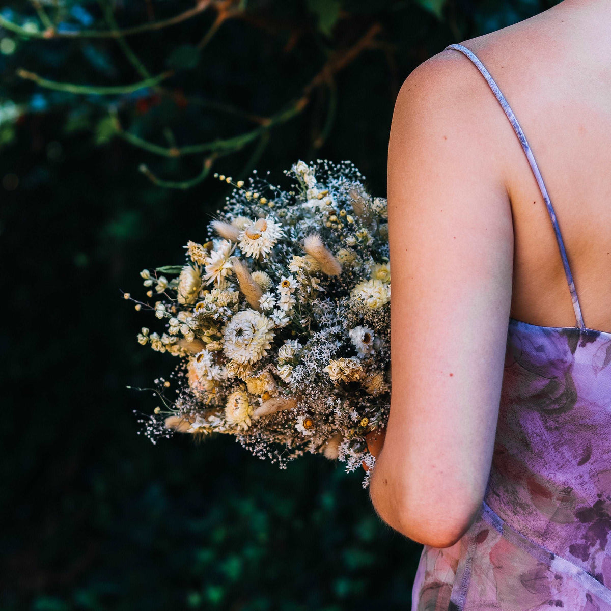 Blush and cream dried flower bouquet with strawflower heads and airy filler sprigs in hand