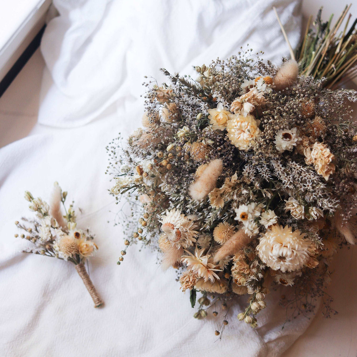 Rustic dried flower bouquet with strawflower heads, dark foliage, and small filler sprigs