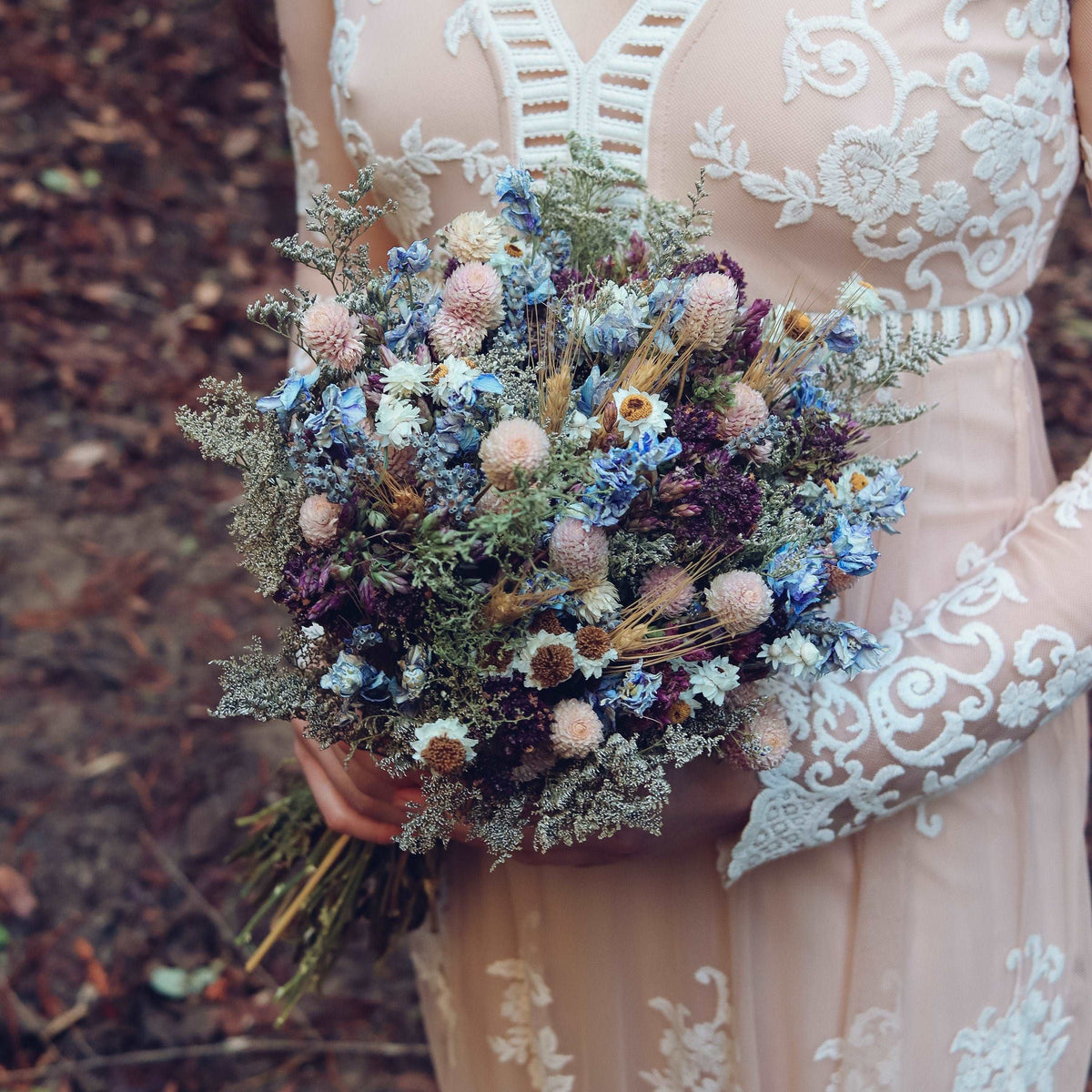 Dried wildflower bouquet in blue and purple held with lace dress