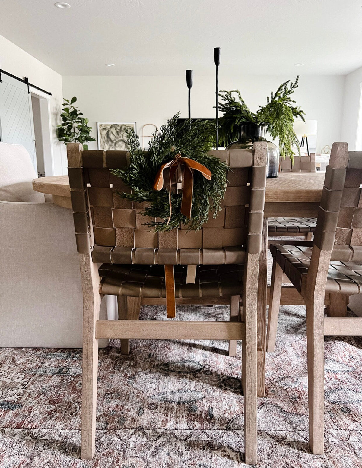 Mini cedar wreath with ribbon on the back of a dining chair in a home setting