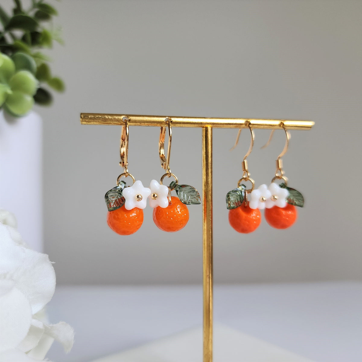 Orange fruit dangle earrings with white flower and green leaves, gold hook style