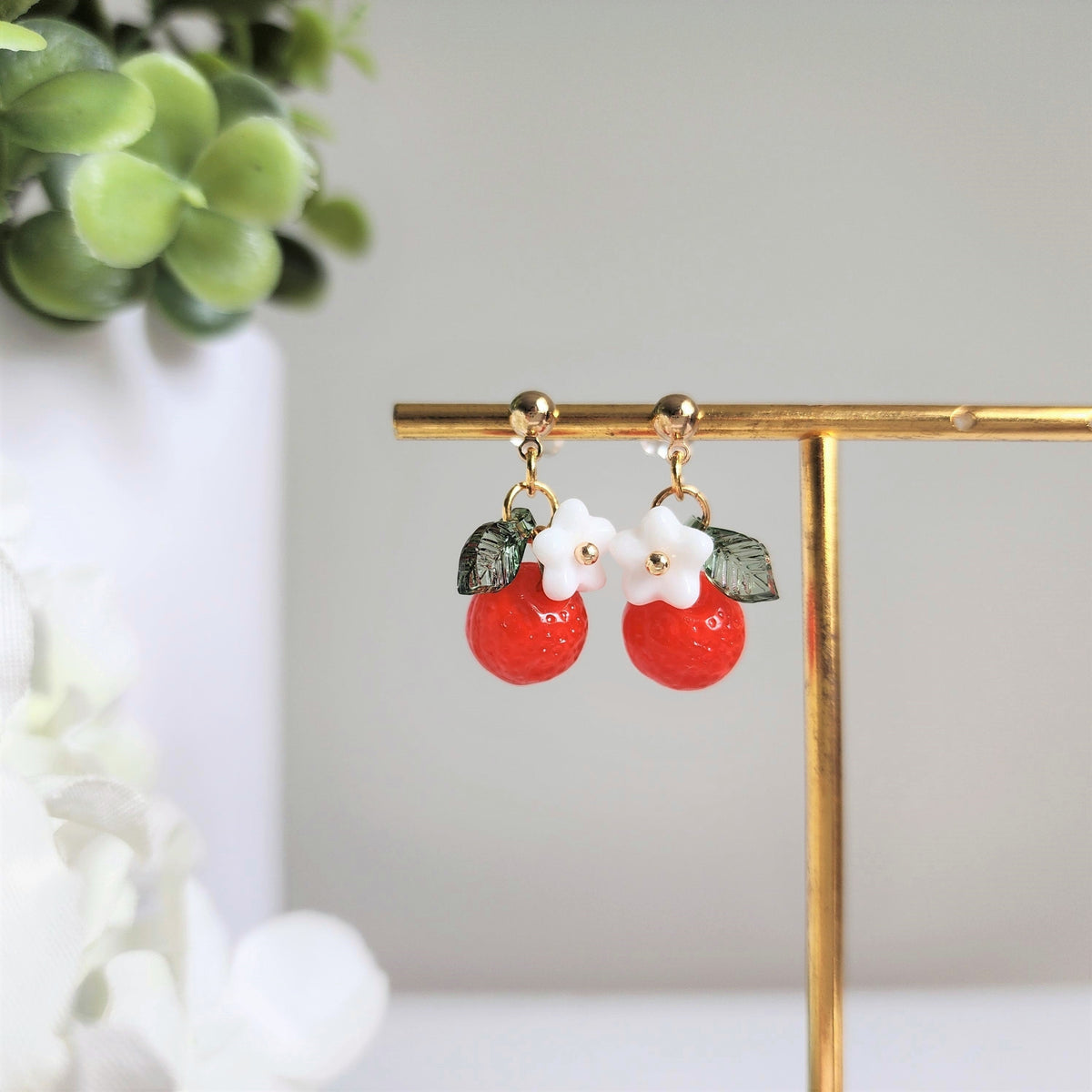 Orange fruit drop earrings with white flower and green leaf charms, gold hooks