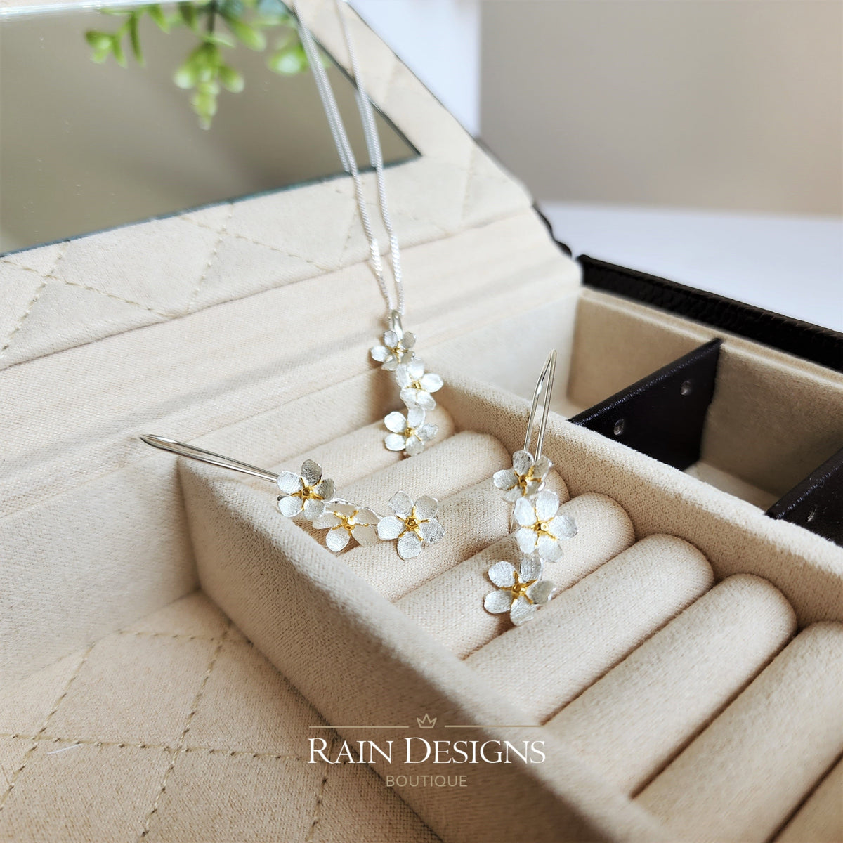 Silver flower hook earrings with gold-accent blossoms in jewelry box