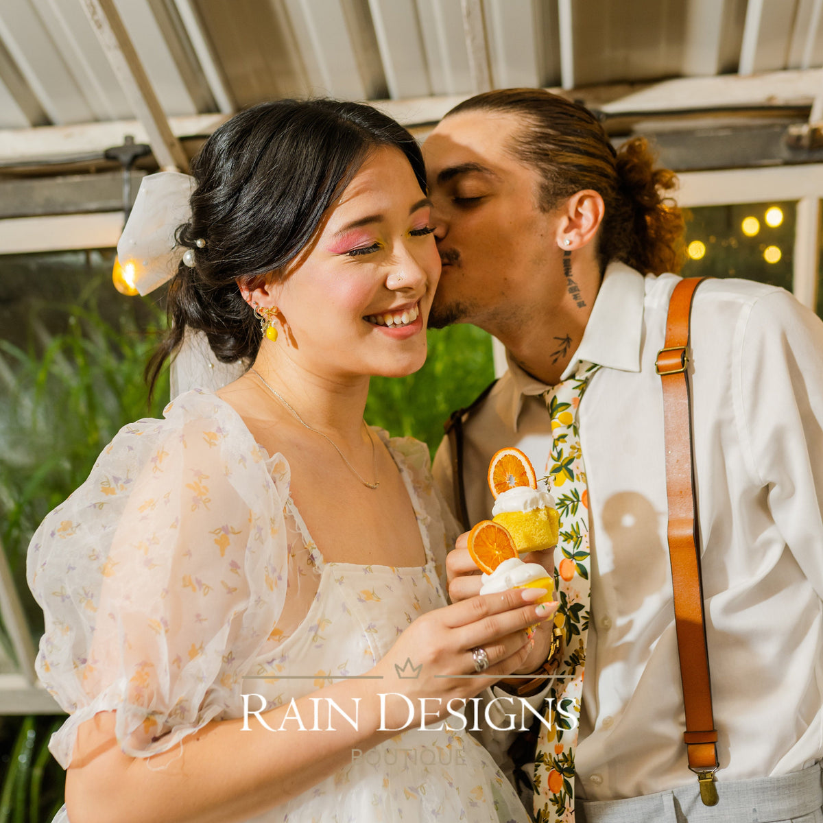 Couple outdoors; woman wears yellow lemon dangle earrings with green leaves and flower details