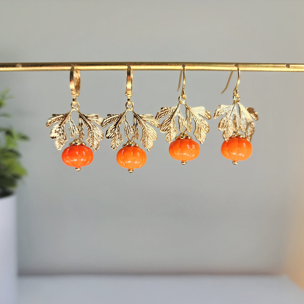Multiple gold-tone dangling pumpkin earrings with orange beads and leaf charms