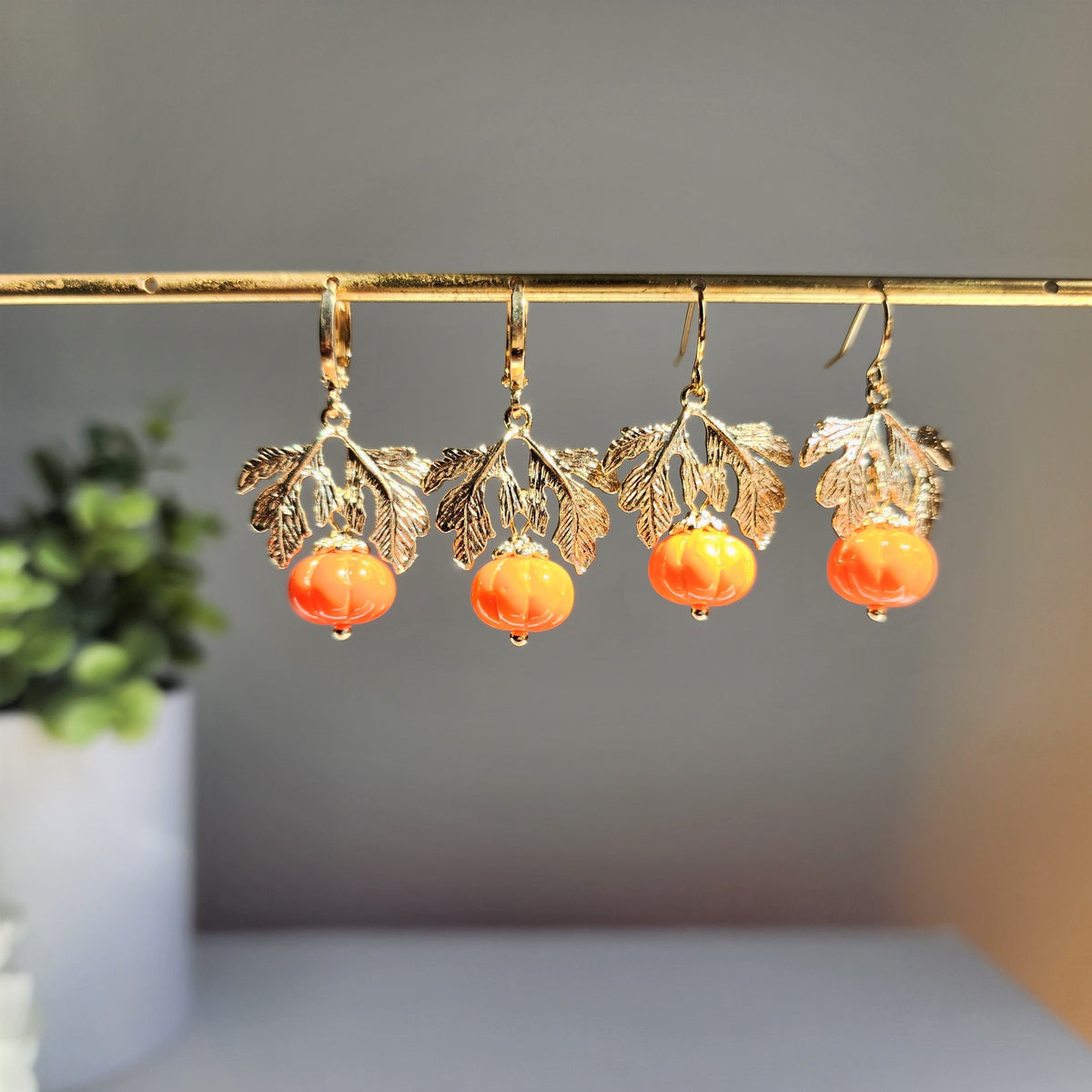 Group of gold-tone dangling pumpkin earrings with orange beads and leaf charms