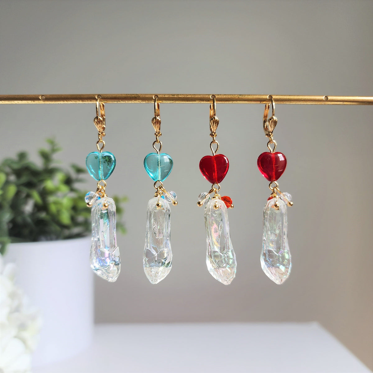 Cinderella glass slipper earrings on a gold rack with mixed heart colors and clear slippers