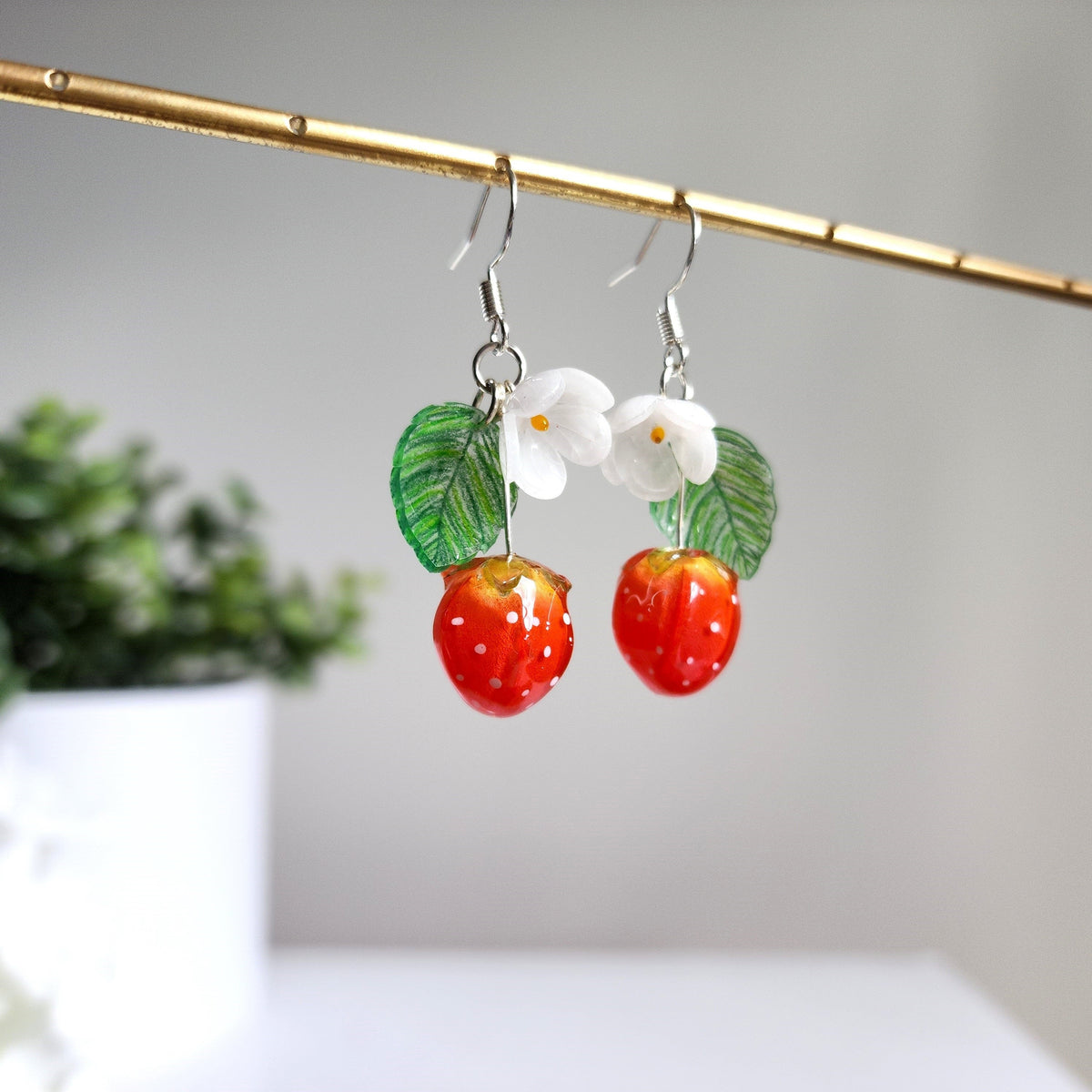 Strawberry drop earrings with white flowers, green leaves, and red resin berry charms
