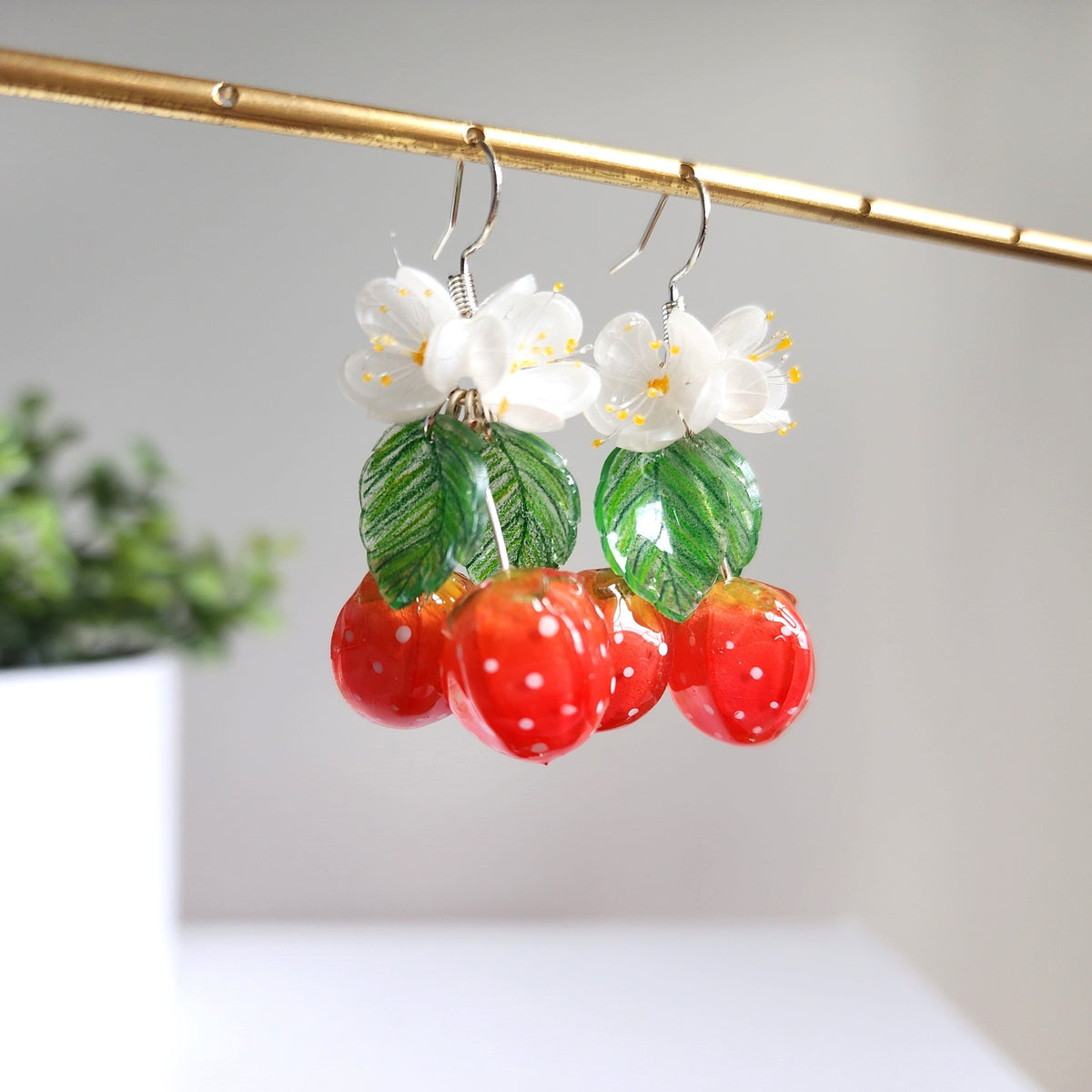 Strawberry cluster drop earrings with white blossoms, green leaf details, and red berries