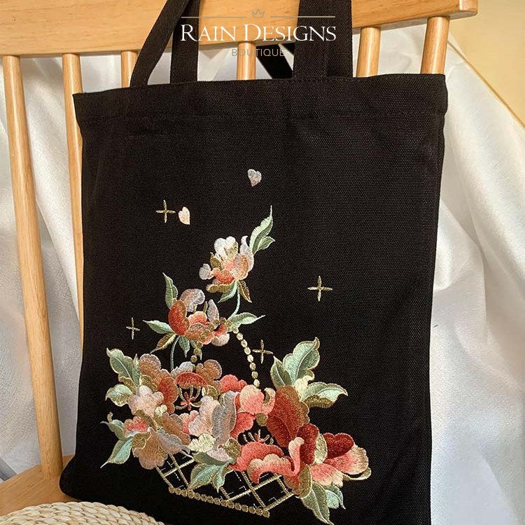Black embroidered tote bag with colorful flower basket and cross accents.
