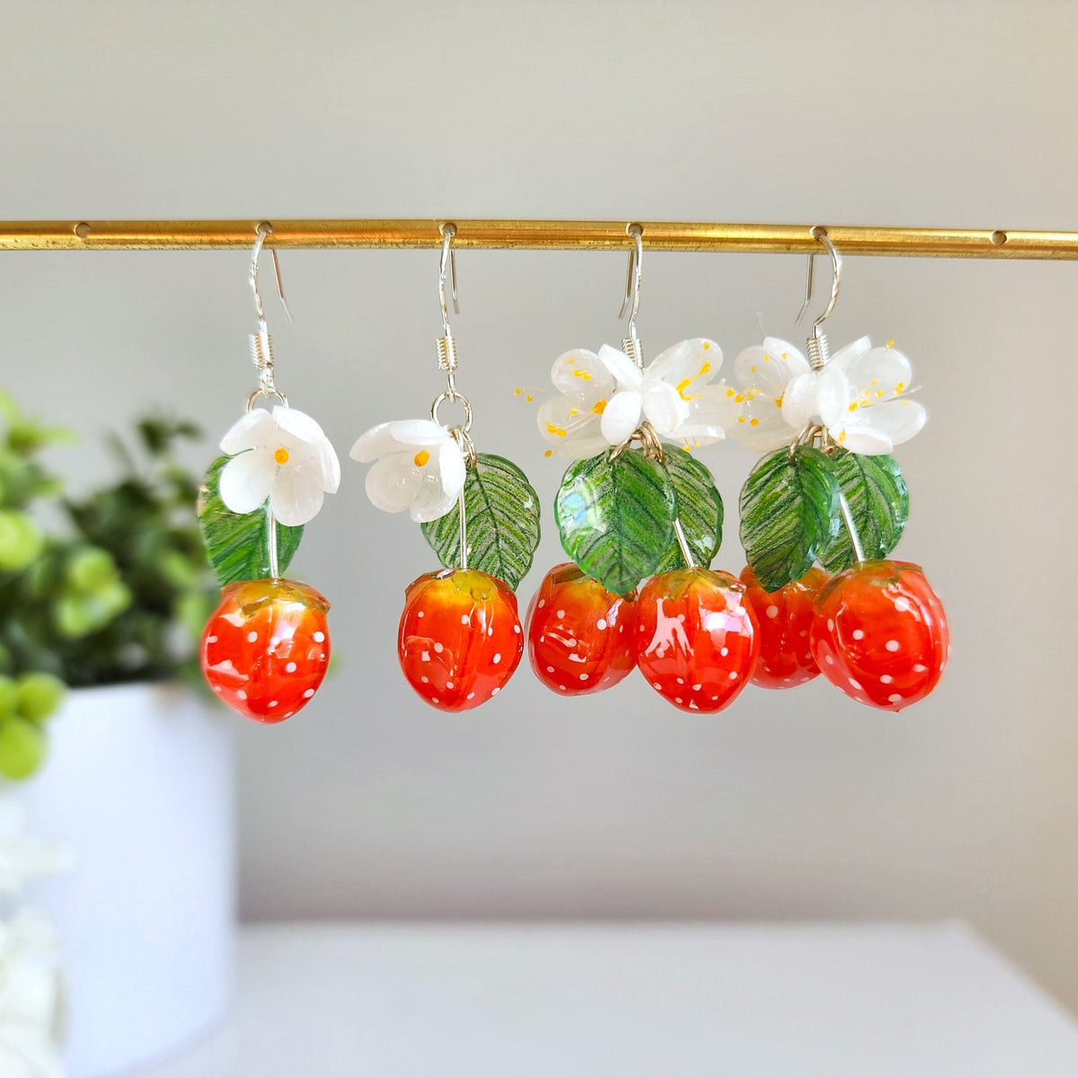 Strawberry cluster drop earrings with white blossoms, green leaves, and multiple red berries