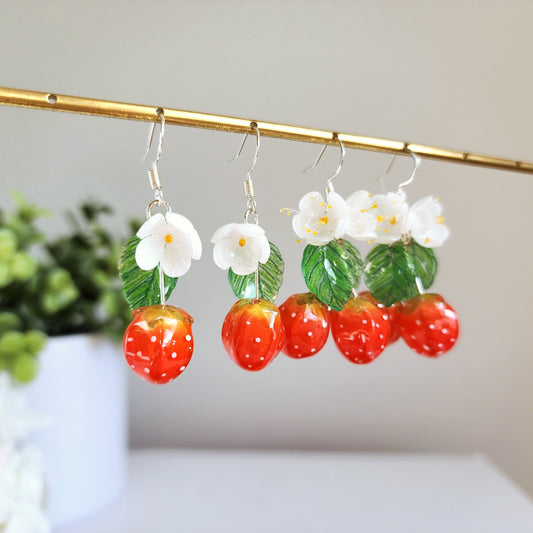 Strawberry cluster drop earrings with white flowers, green leaves, and red resin berries