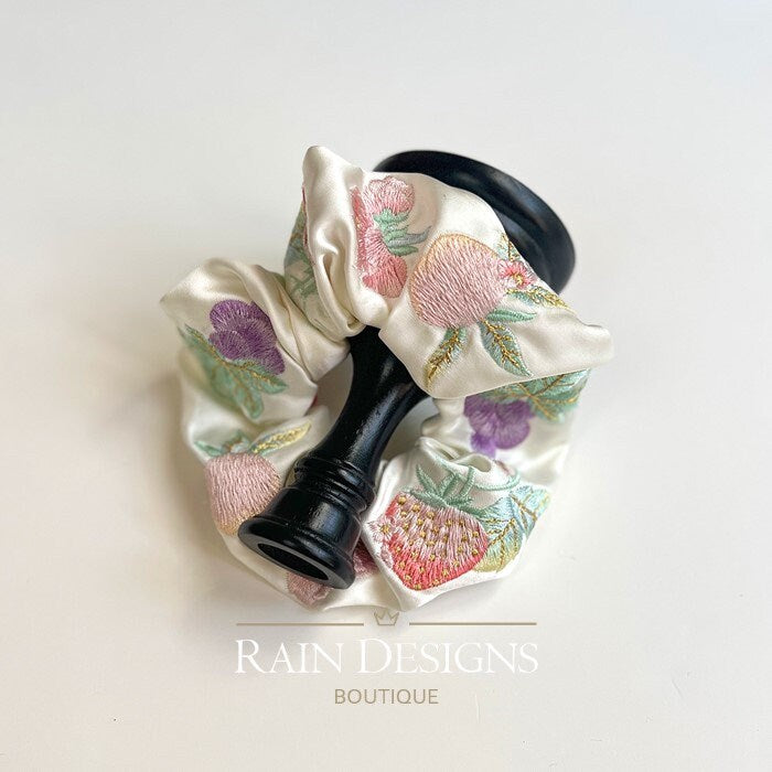 Ivory fruit-embroidered scrunchie with ruffled gathers and colorful leaf details.