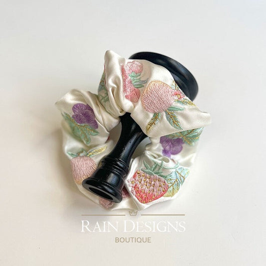 Ivory fruit-embroidered scrunchie with ruffled gathers and colorful leaf details.