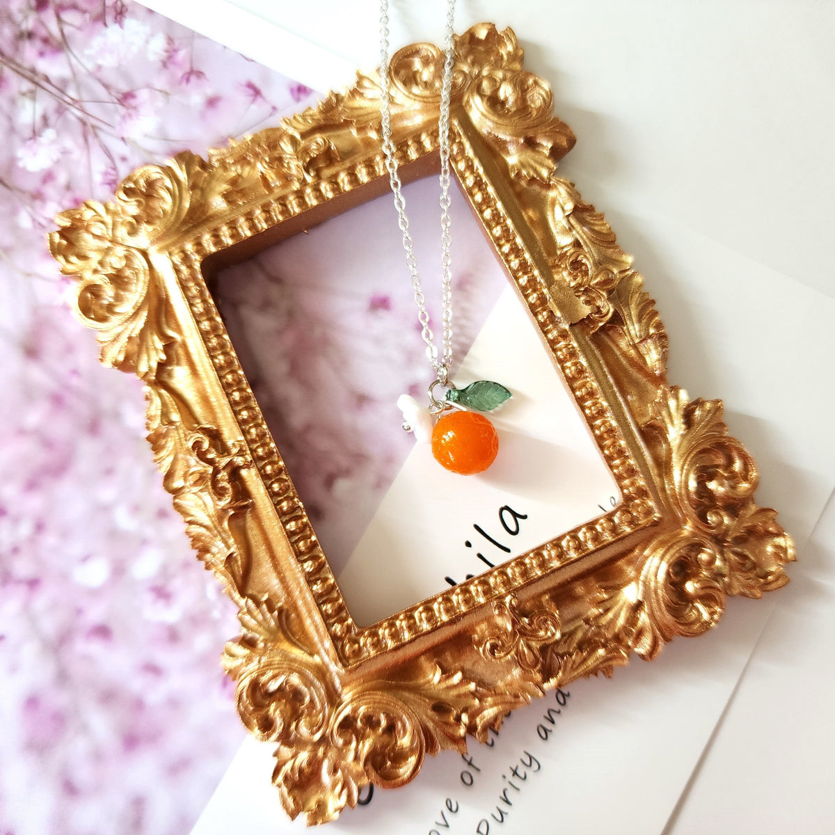 Gold-tone orange fruit charm necklace with multiple orange charms and green leaves