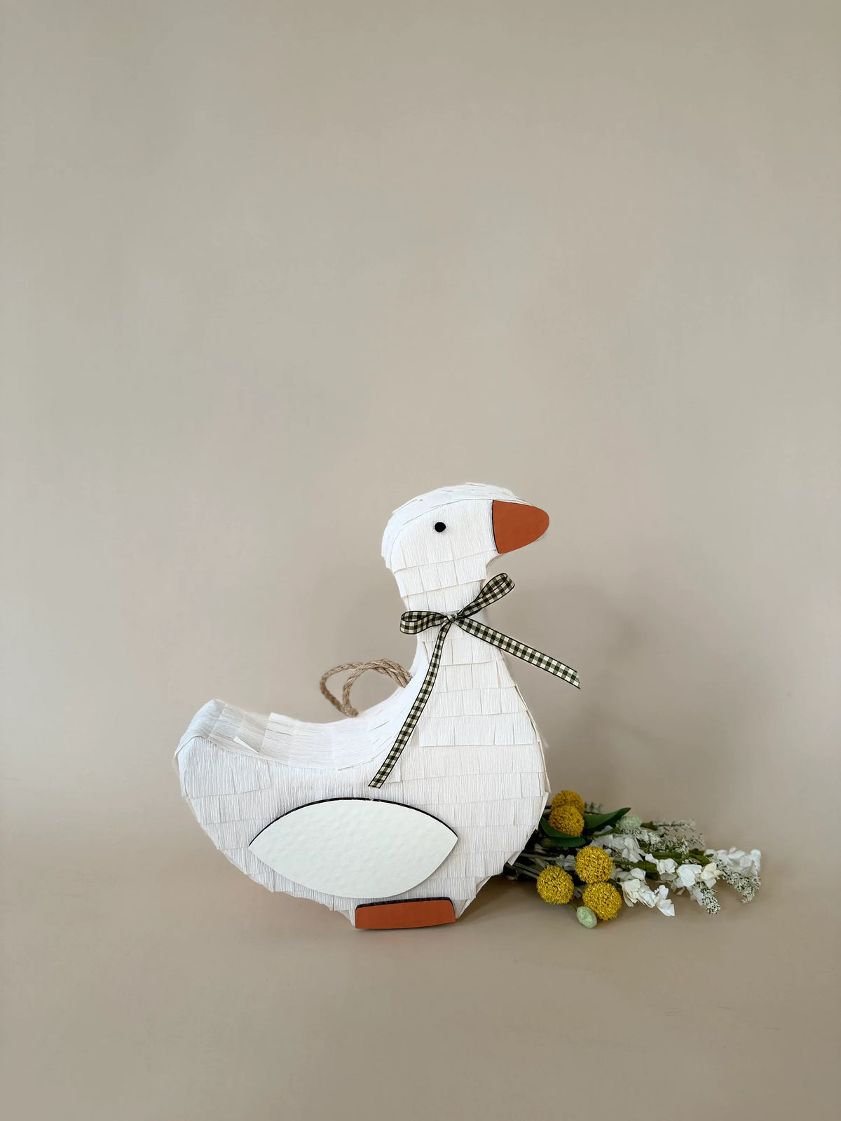 Handmade goose piñata with checkered bow and oval white belly