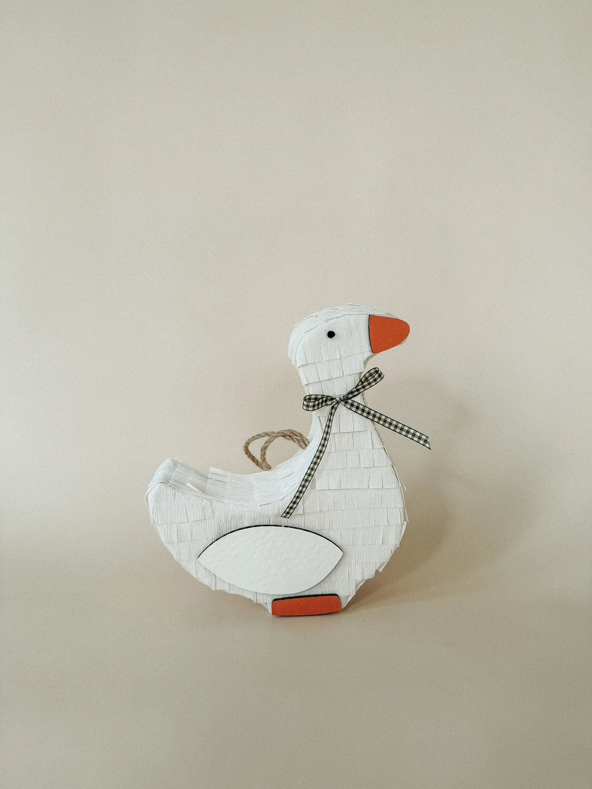 Handmade goose piñata with checkered bow, orange beak, and orange feet