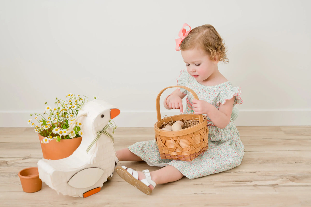Goose piñata with white body, orange beak, and green gingham ribbon