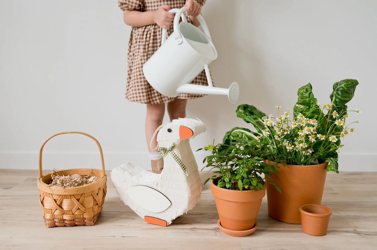Goose piñata in white with orange beak and feet, standing on the floor
