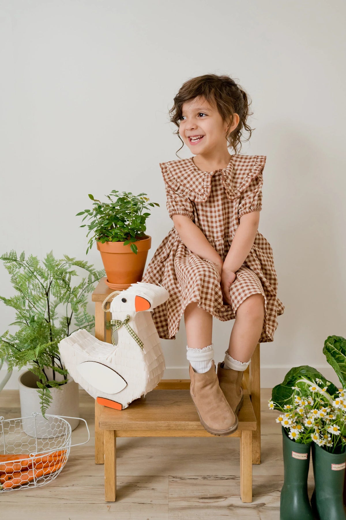 Goose piñata with white body, orange beak and feet, and a green ribbon