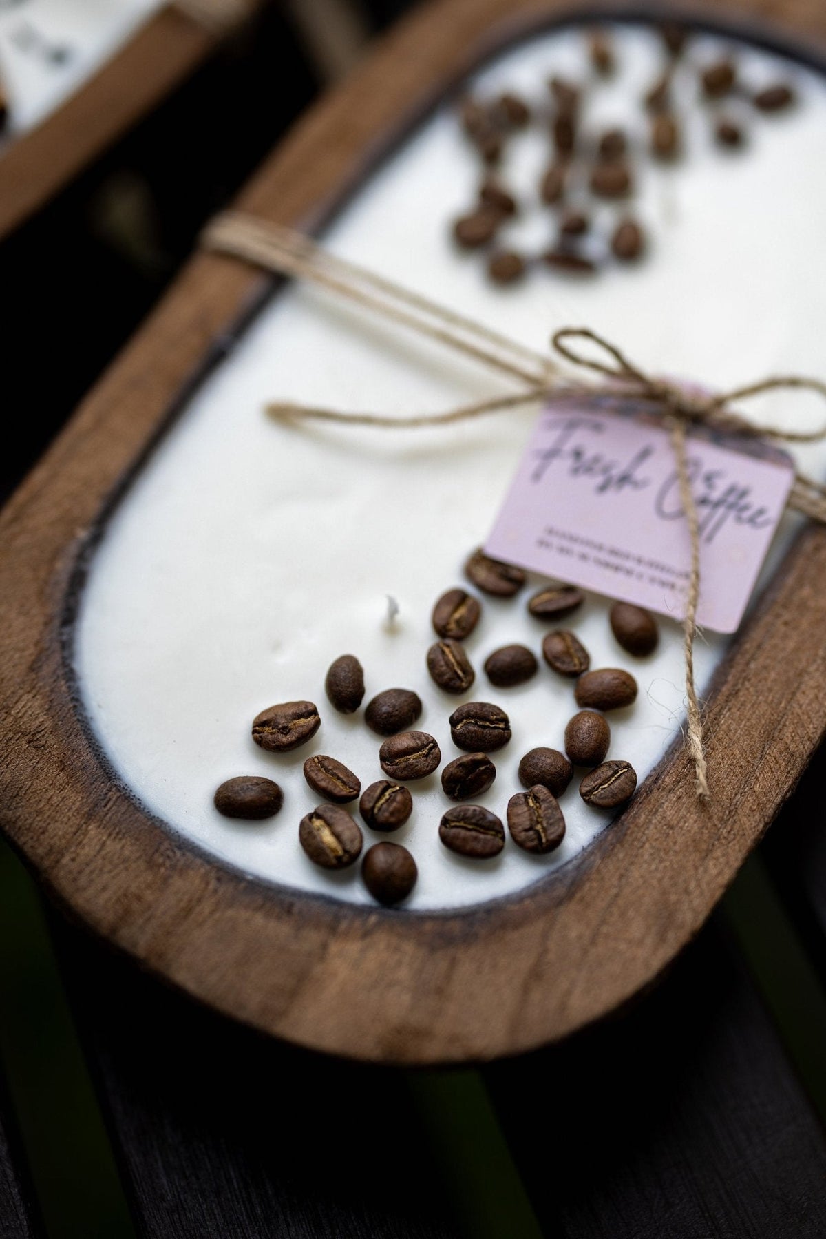 Close-up of coffee-scented candle in wooden bowl with coffee beans and small paper label