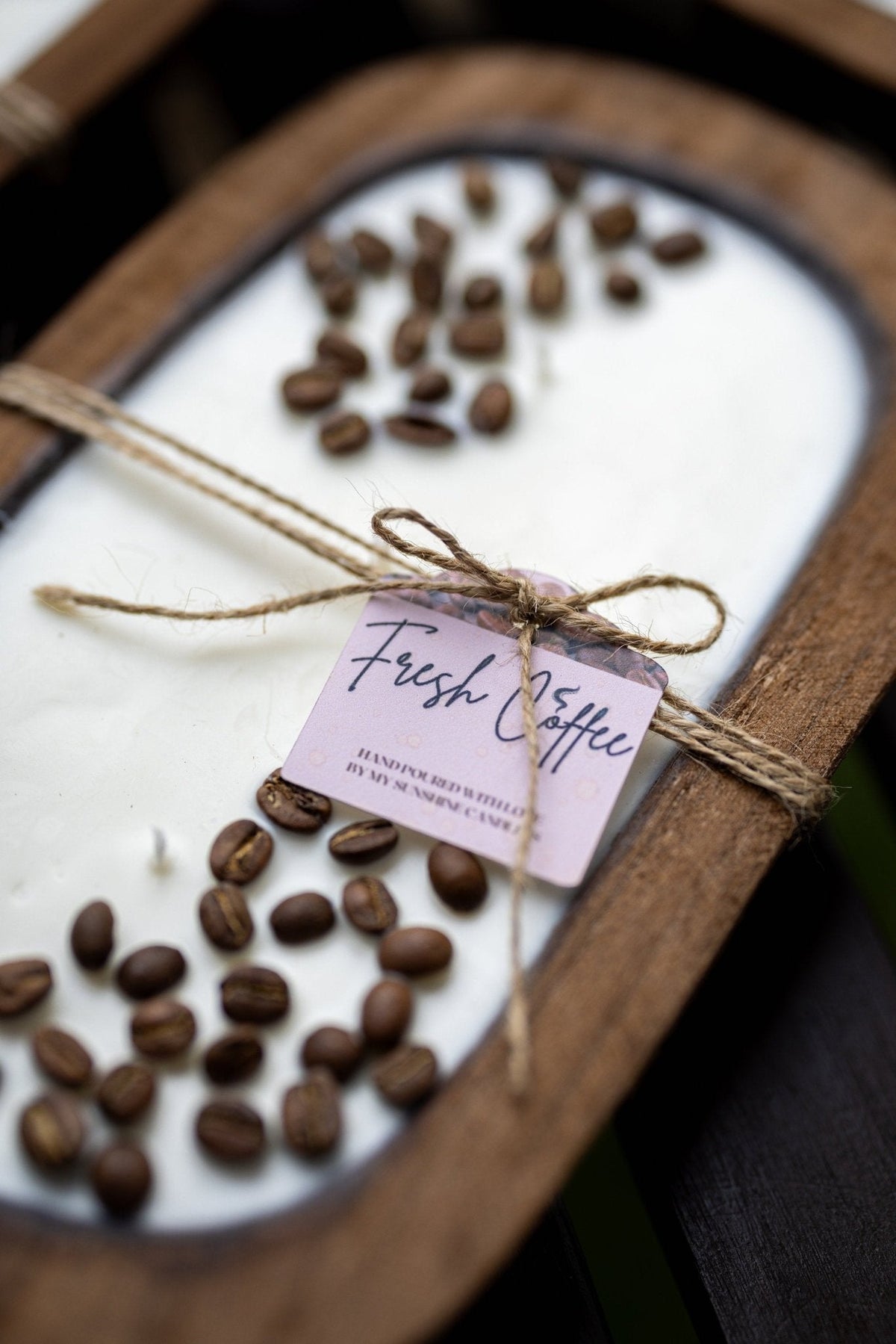 Coffee-scented candle in oval wooden holder with visible coffee beans and wrapped tag