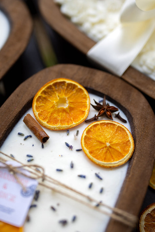 Soy candle in dough bowl with orange slices and cinnamon stick on speckled wax