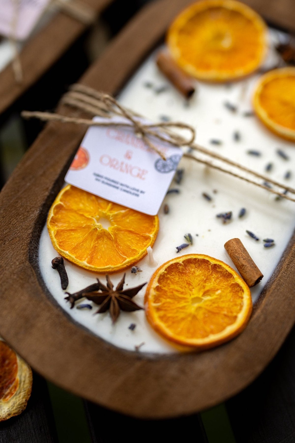Soy candle in wooden dough bowl with orange slices, anise stars, and tied scent card