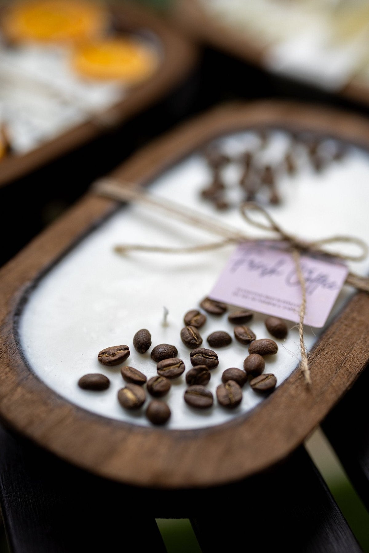 Coffee-scented candle bowl with coffee beans and twine bow over the wax surface