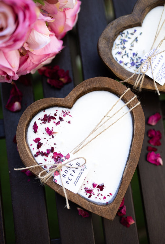 Heart-shaped dough bowl candle with white wax, rose petal flakes, and twine tied around label