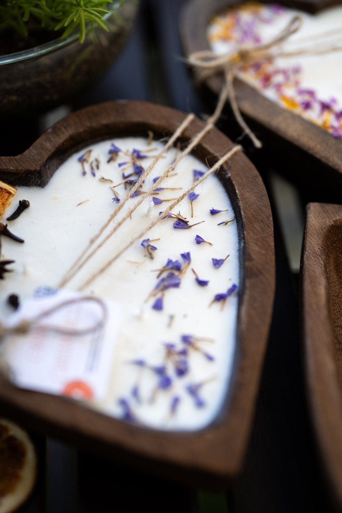 Close-up of heart-shaped white soy candle wax with 3 cotton wicks and blue dried petals