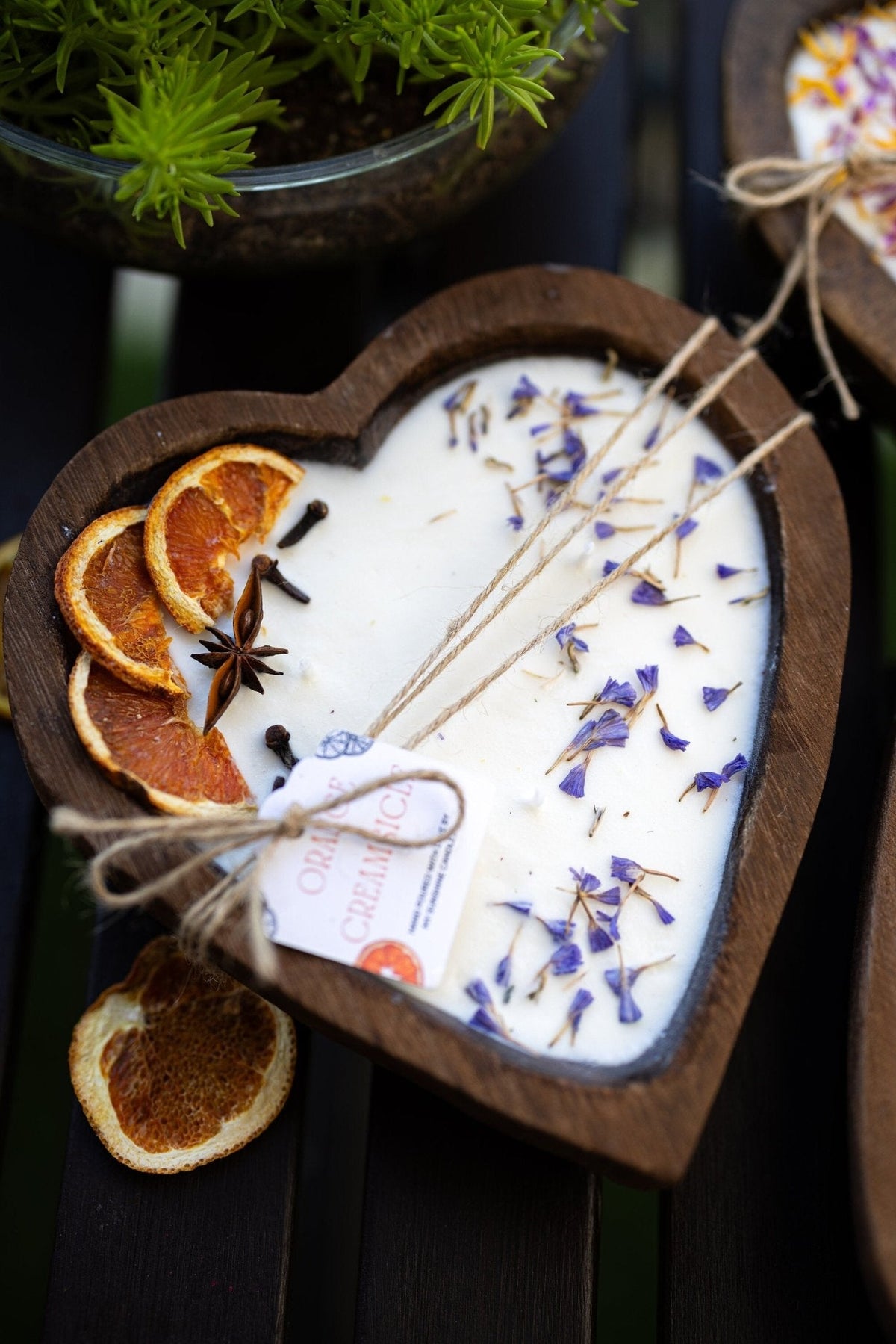 Heart-shaped white soy candle in dark wood holder with orange slices and 3 cotton wicks
