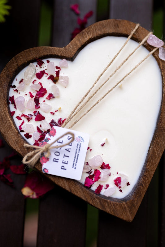 Heart-shaped wooden dough bowl candle with white wax, rose petals, and three cotton wicks.