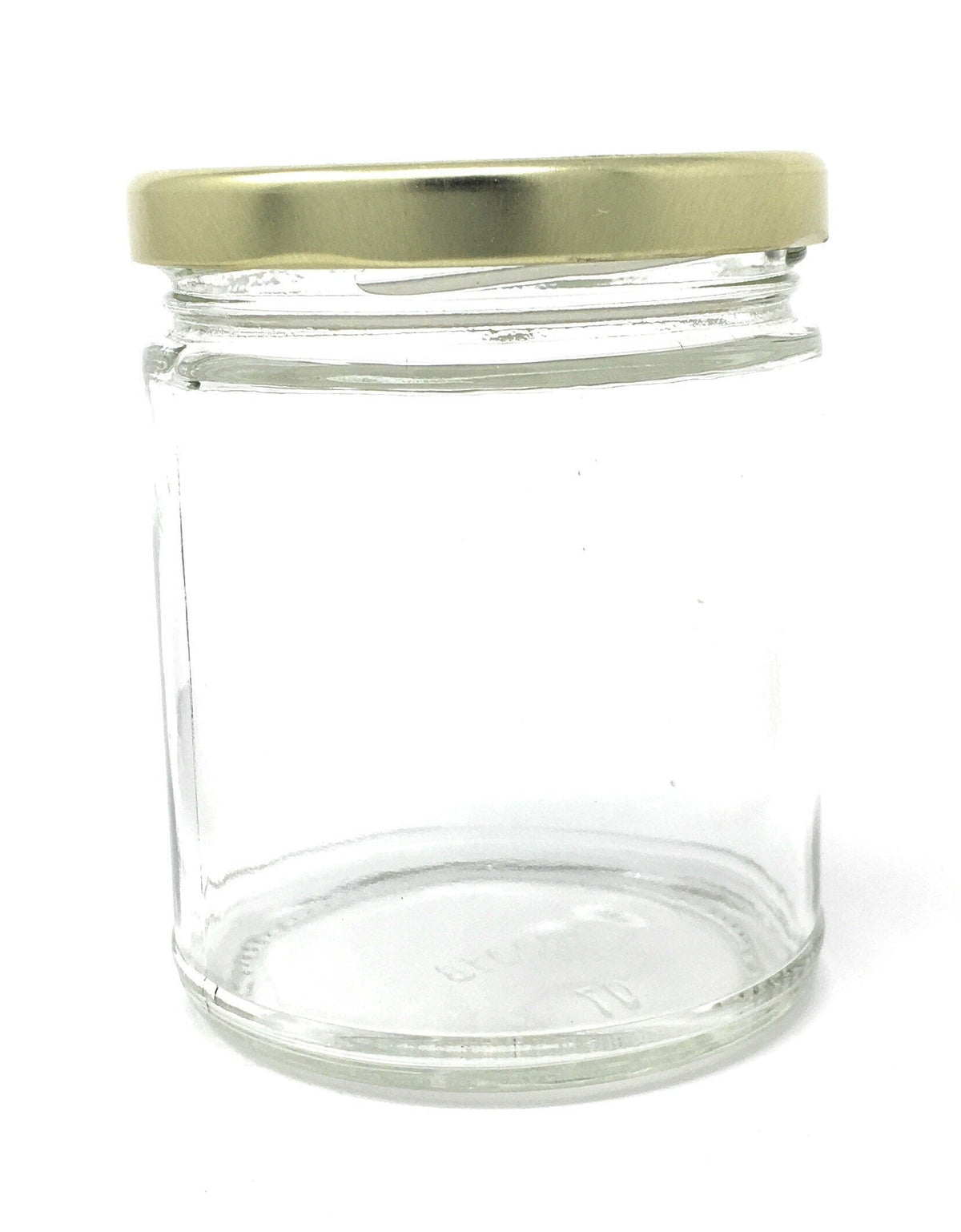 Clear glass candle jar with gold-toned screw lid, empty.