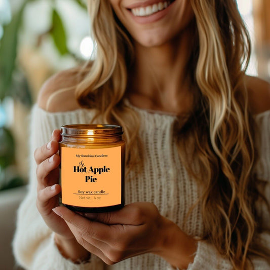 Amber jar candle with black label, held in a hand, wick area visible.